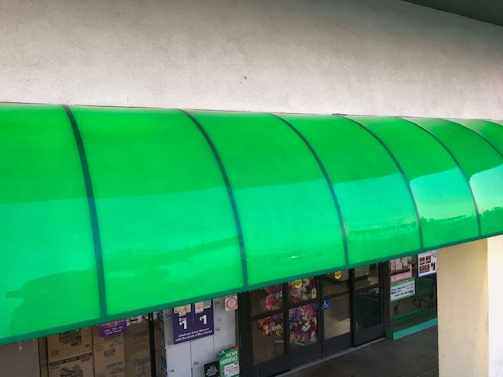 A green awning is covering the entrance to a store.