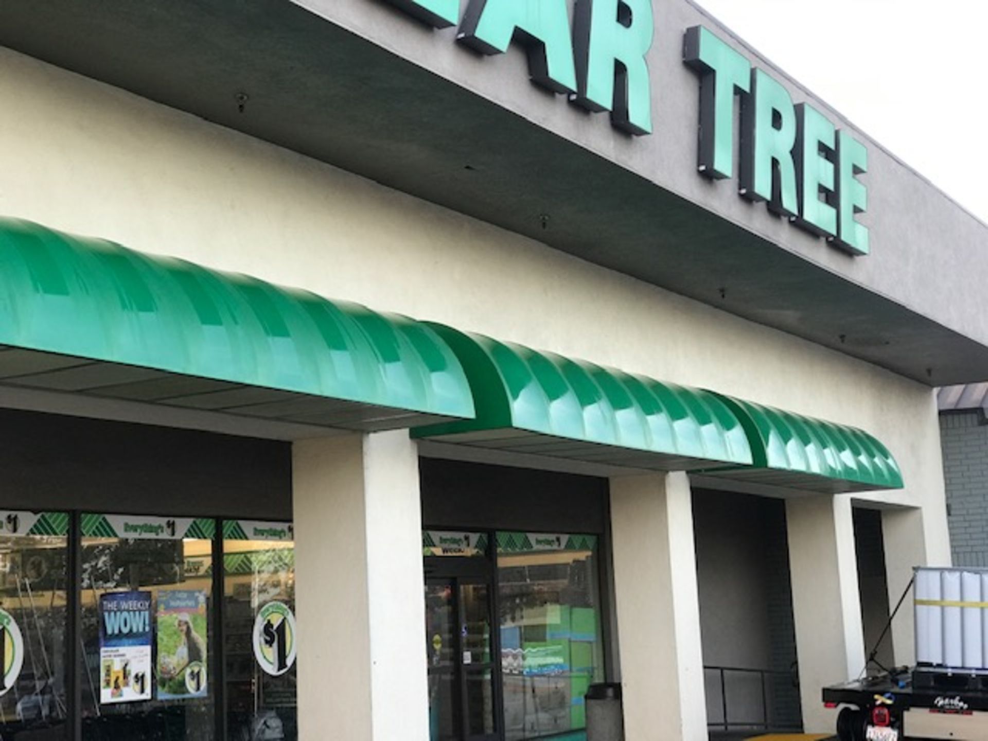 The front of a dollar tree store with a green awning