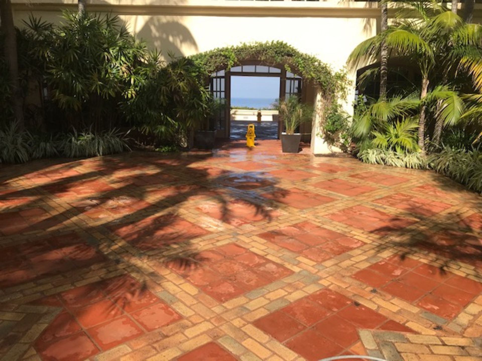 A brick walkway leading to a building with a view of the ocean