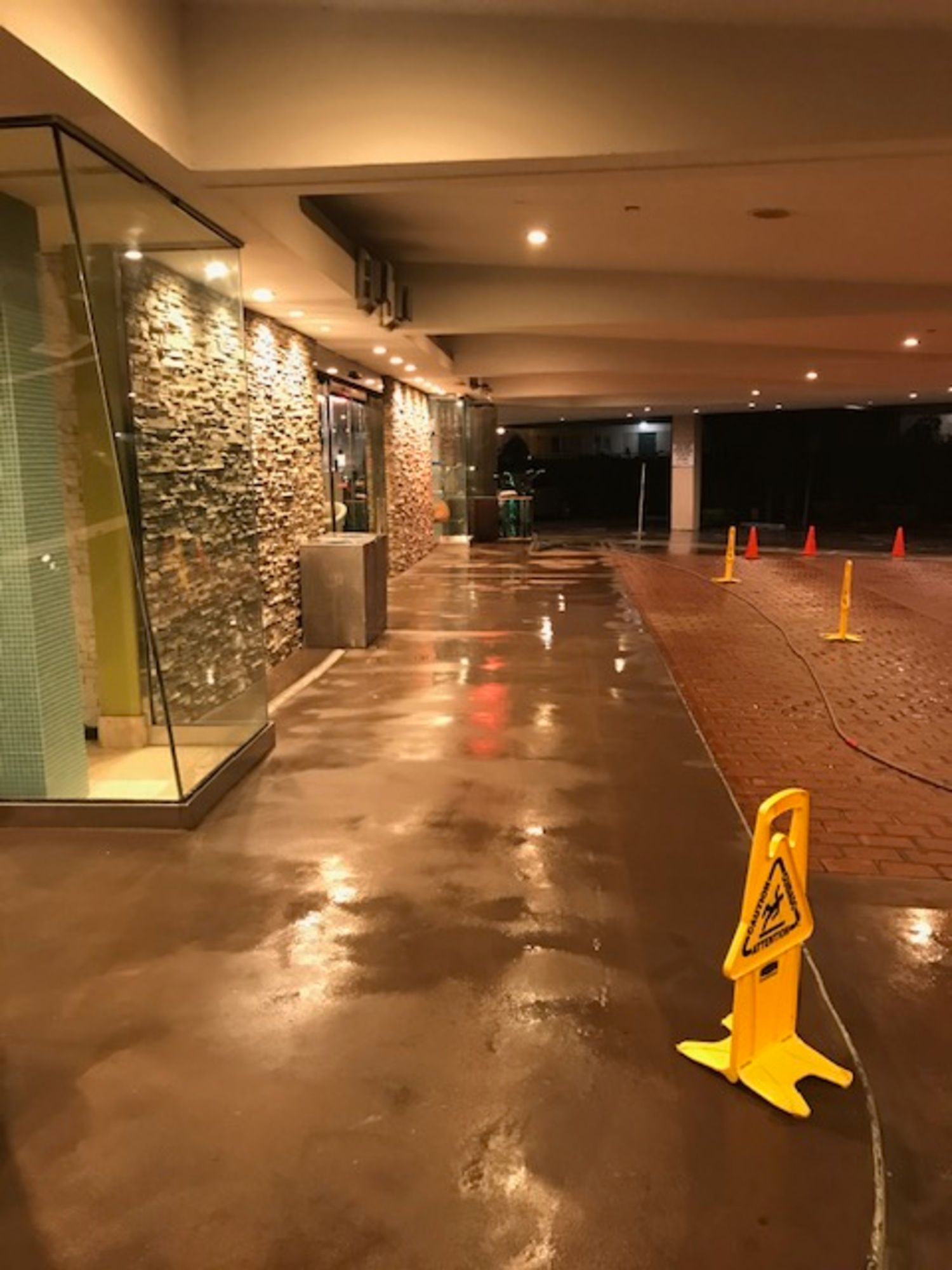 A wet floor with a yellow caution sign on it.