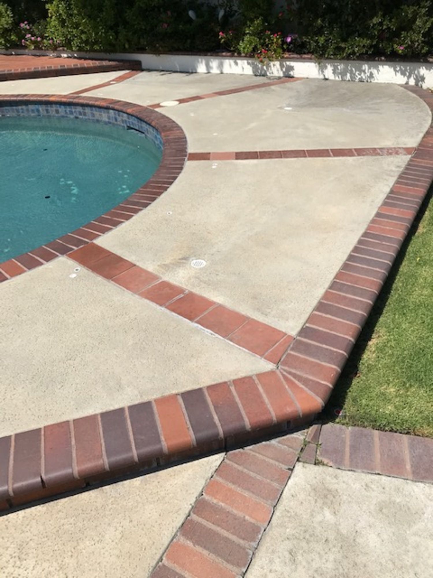 A swimming pool with a brick walkway around it