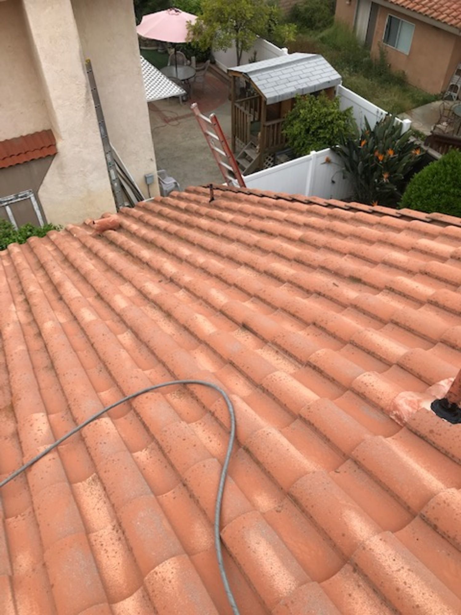 A close up of a tiled roof with a hose attached to it.