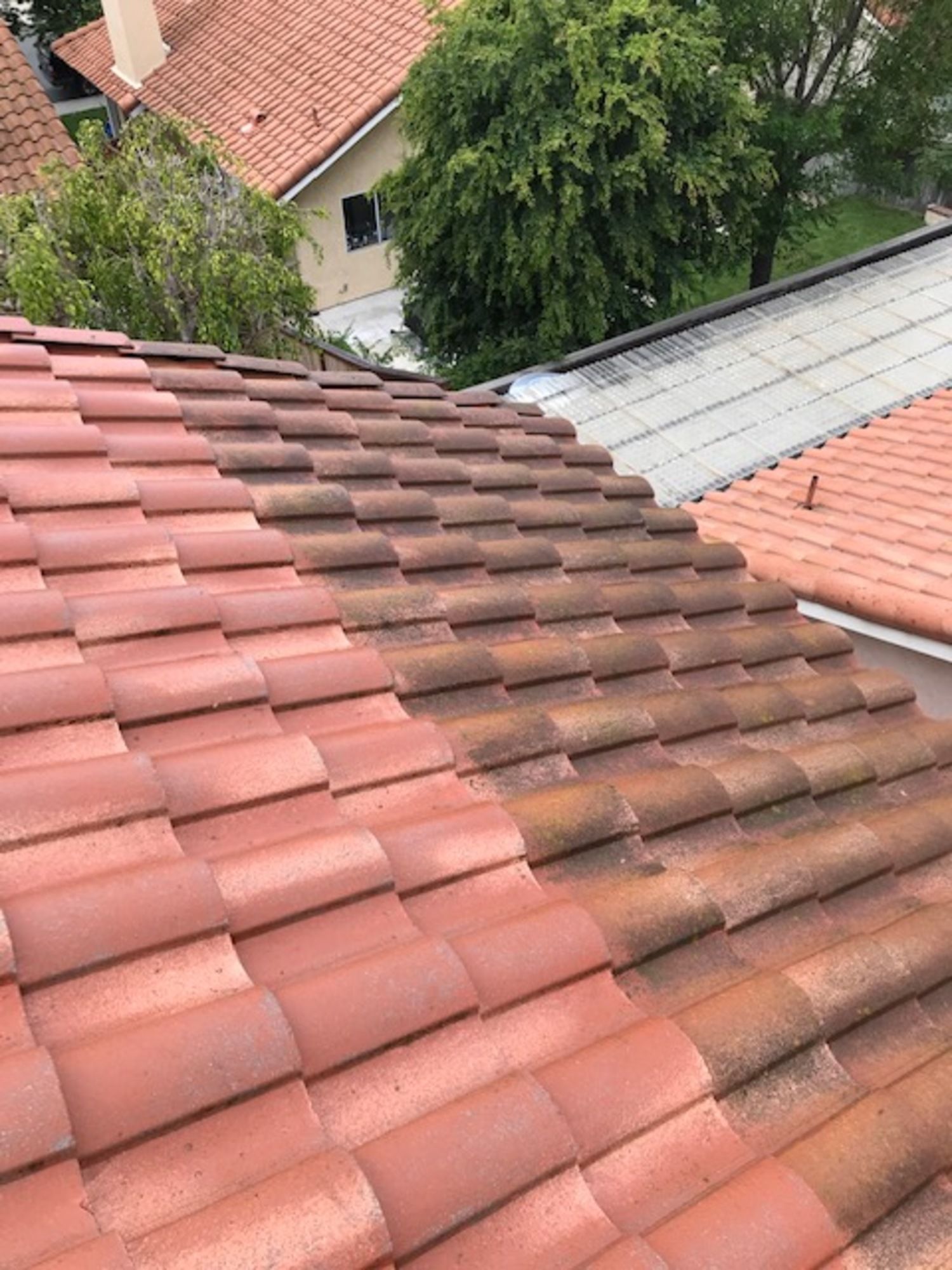 A before and after picture of a tile roof being cleaned.