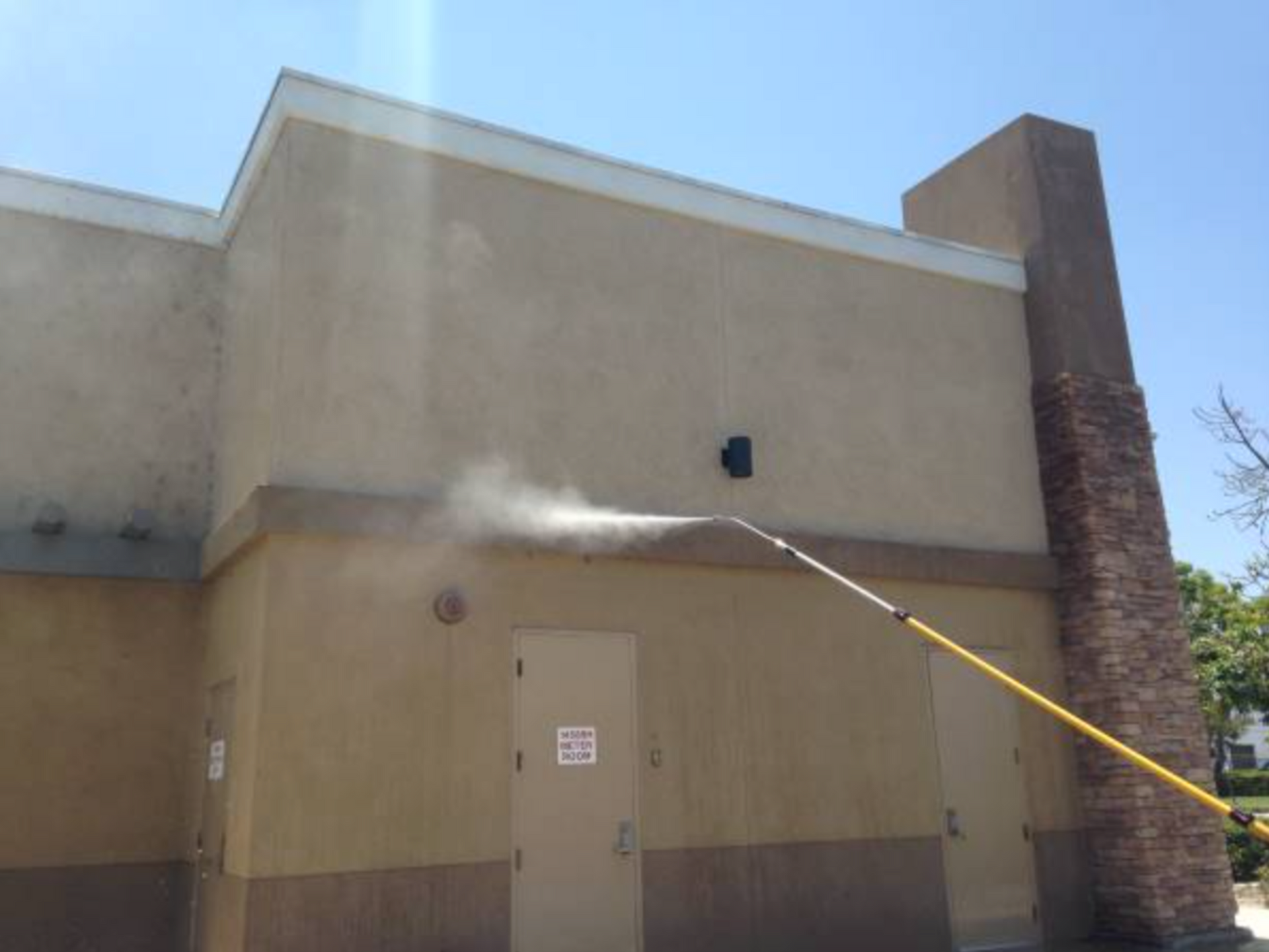 A person is spraying water on the side of a building.
