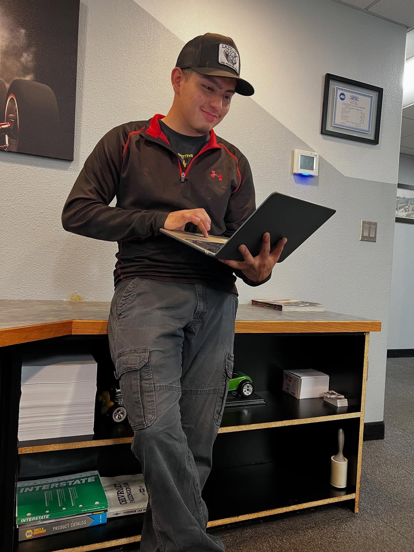 Person Leaning Against a Counter While Working on a Laptop | Gearheadz Garage