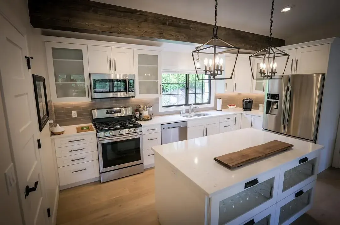 Bright modern kitchen with white cabinets, island, farmhouse sink, and stainless steel appliances