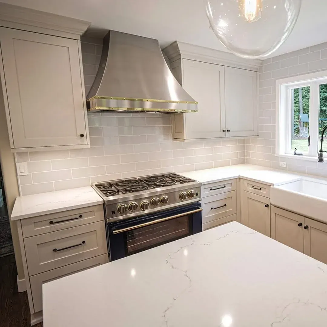 Bright modern kitchen with white cabinets, island, farmhouse sink, and stainless steel appliances