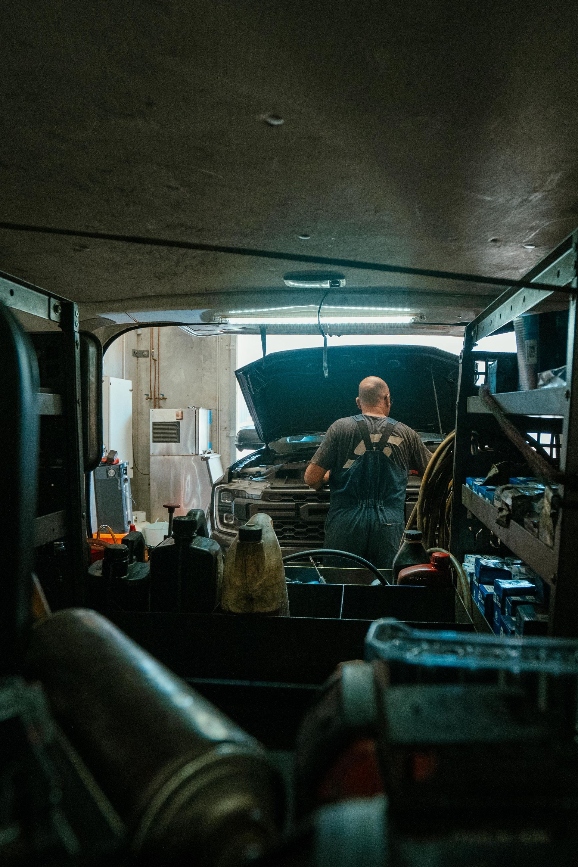 Mechanic working on a car in a garage, visible from inside the shop with tools in foreground. — Navan Mobile Mechanic in Corrimal, NSW
