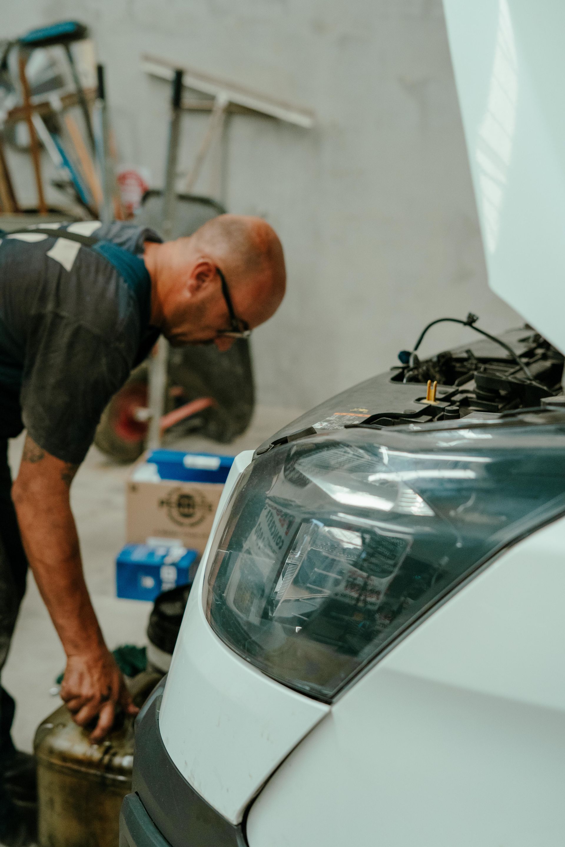 Mechanic working on a white car with the hood open in a garage — Navan Mobile Mechanic in Corrimal, NSW