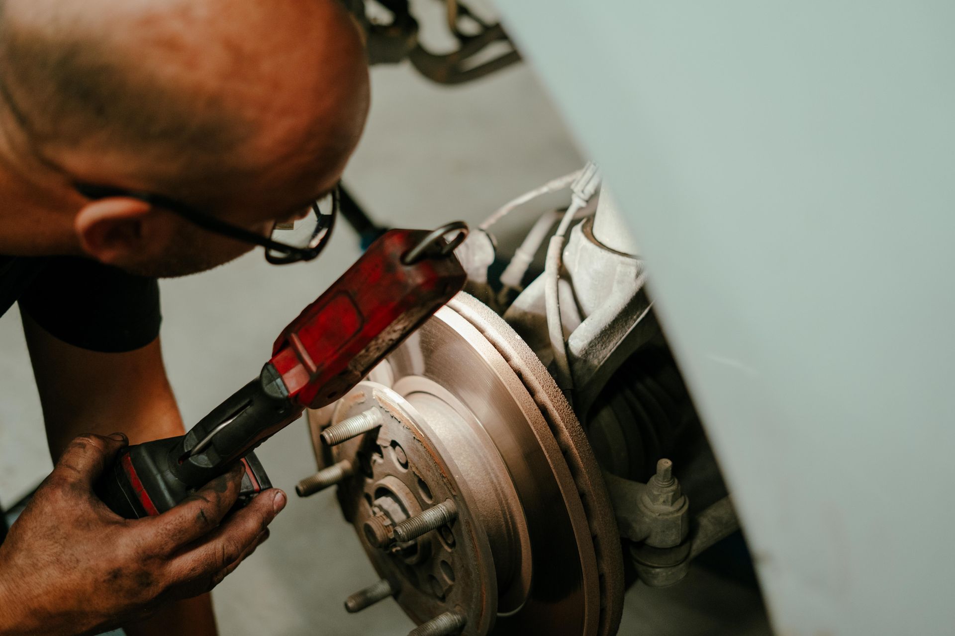 Mechanic inspecting car brake rotor with a flashlight in a garage — Navan Mobile Mechanic in Corrimal, NSW