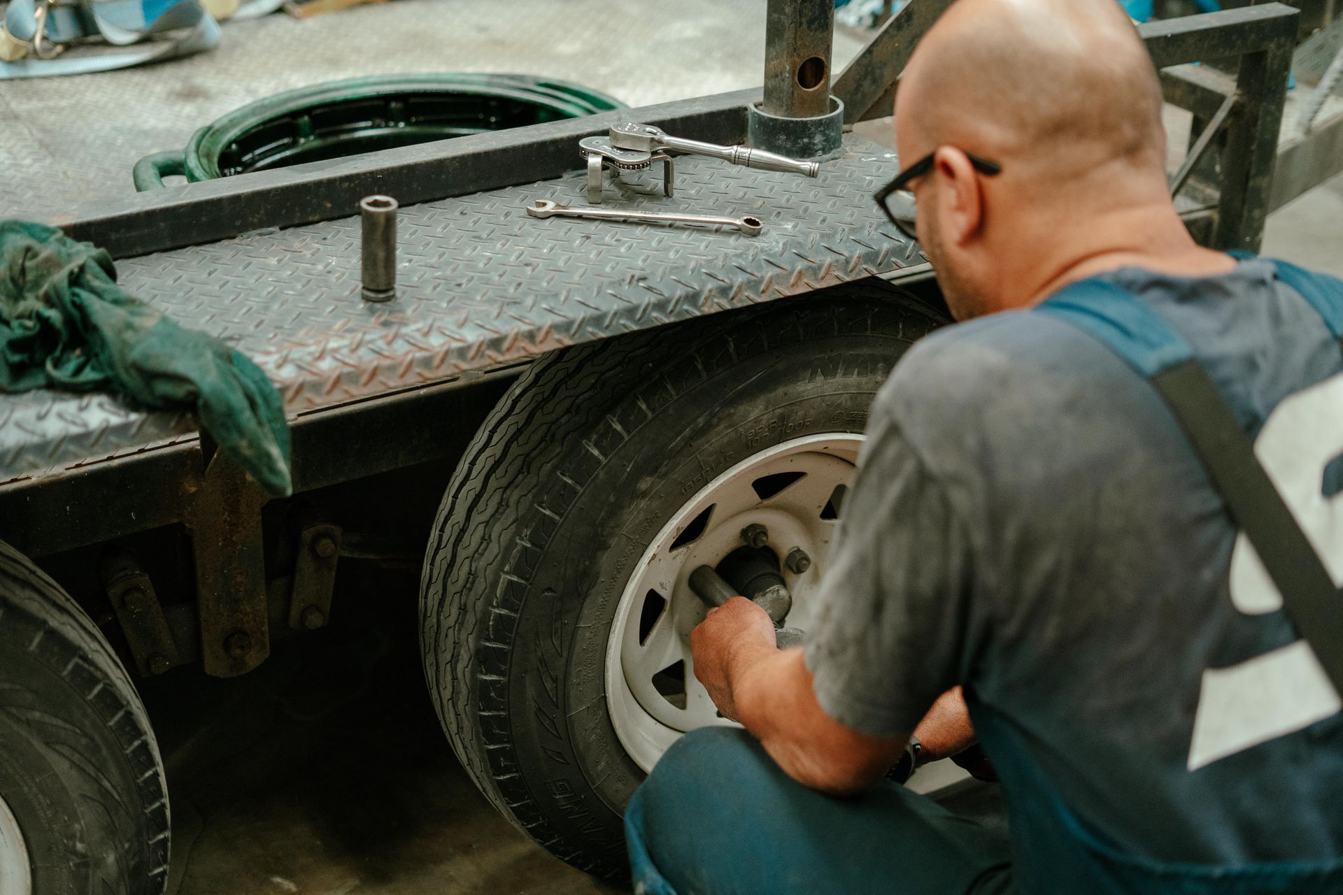 Man working on a trailer tyre in a workshop. He is using tools to remove a lug nut — Navan Mobile Mechanic in Unanderra, NSW