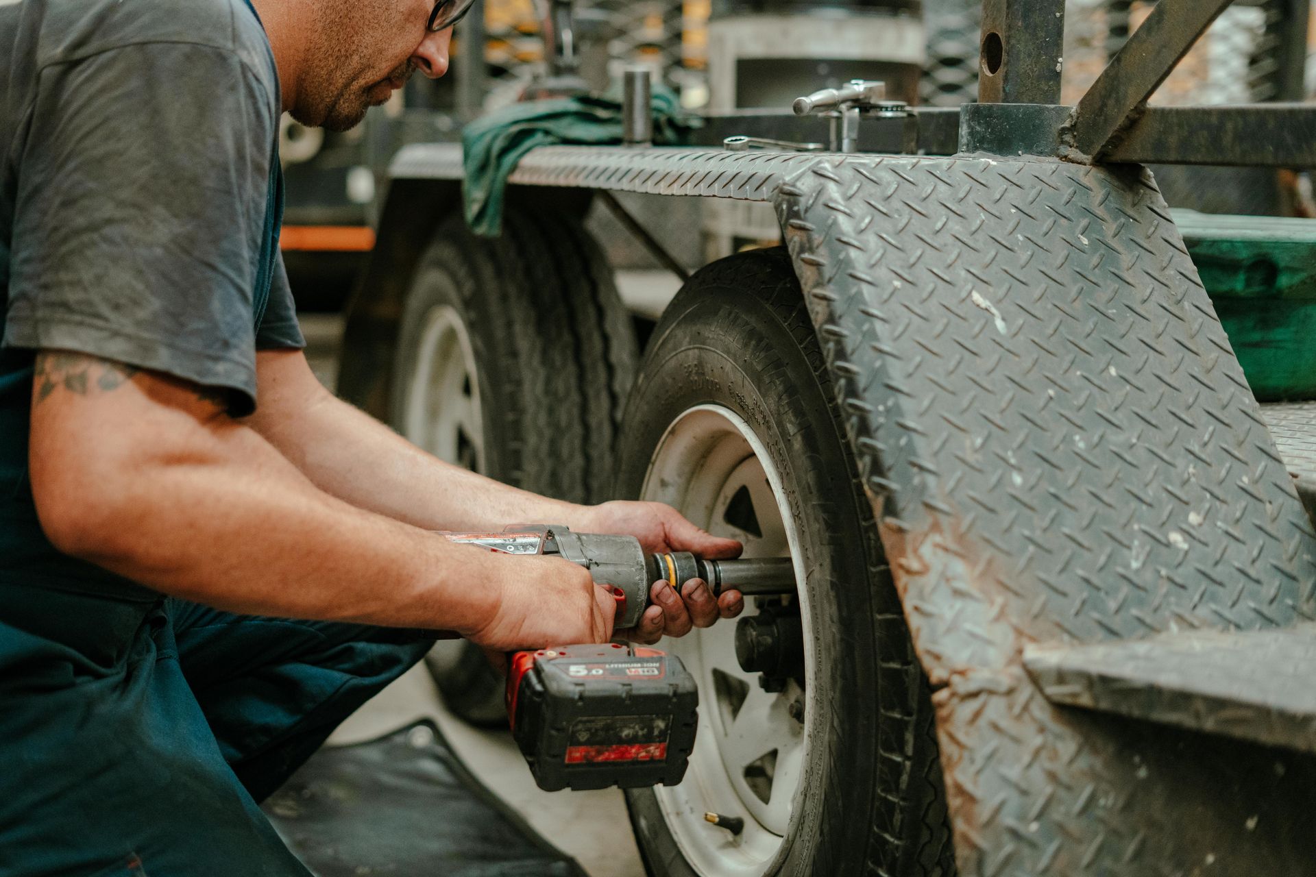 Mechanic using a power tool to work on a trailer tyre — Navan Mobile Mechanic in Corrimal, NSW