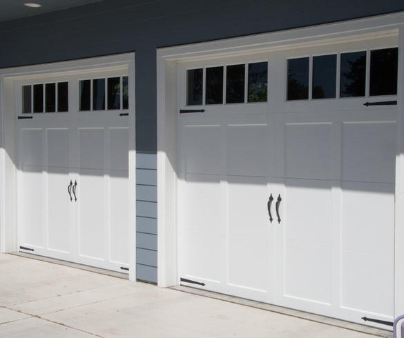 Two white carriage-style garage doors on a house exterior with small window panes above them
