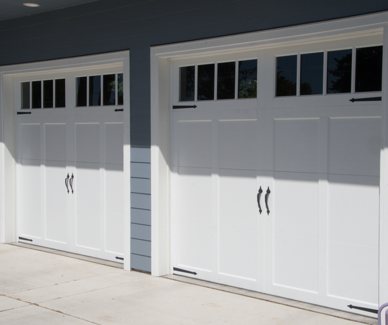 Two white carriage-style garage doors on a house exterior with small window panes above them