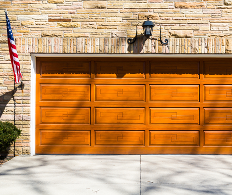 Orange double garage door on a stone house exterior, with an American flag on the left.