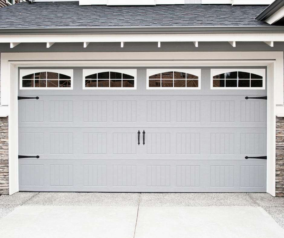 Light gray double garage door with four arched windows on a white house exterior