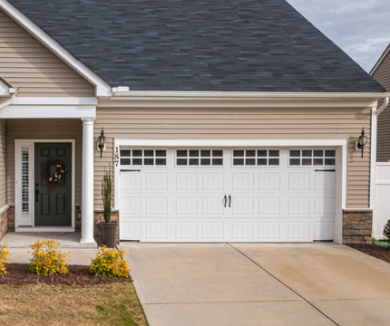 Suburban house exterior with a two-car white garage and front entry porch