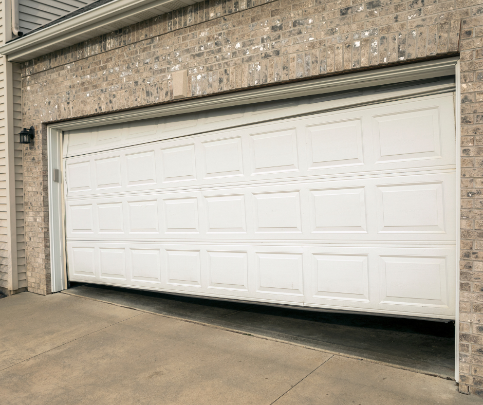 White double garage door needing repair on a brick house driveway