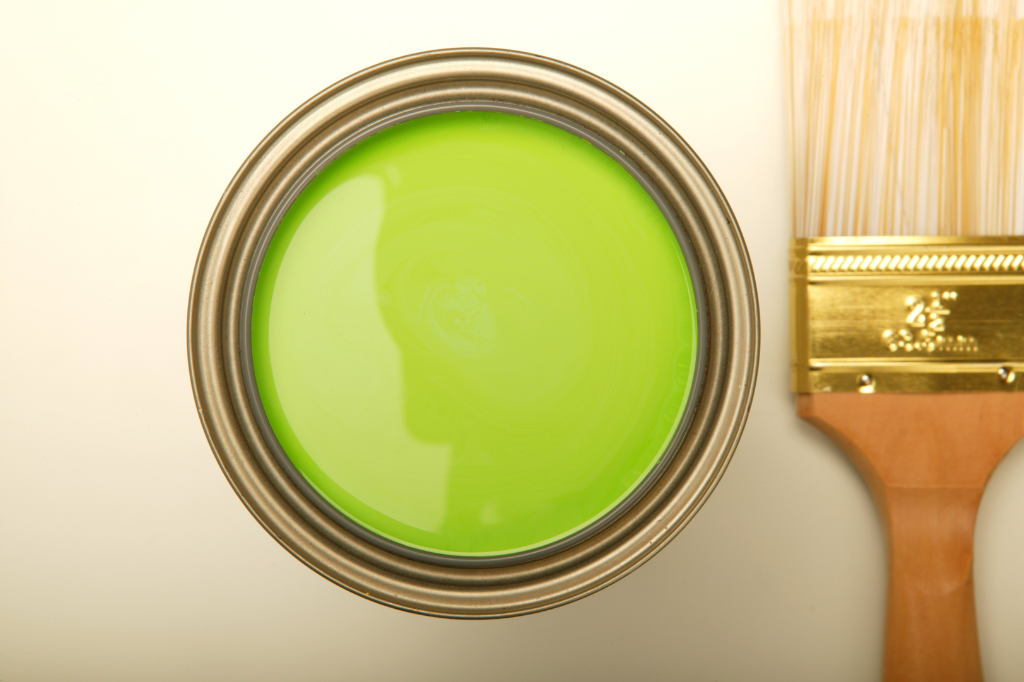 A can of green paint next to a brush
