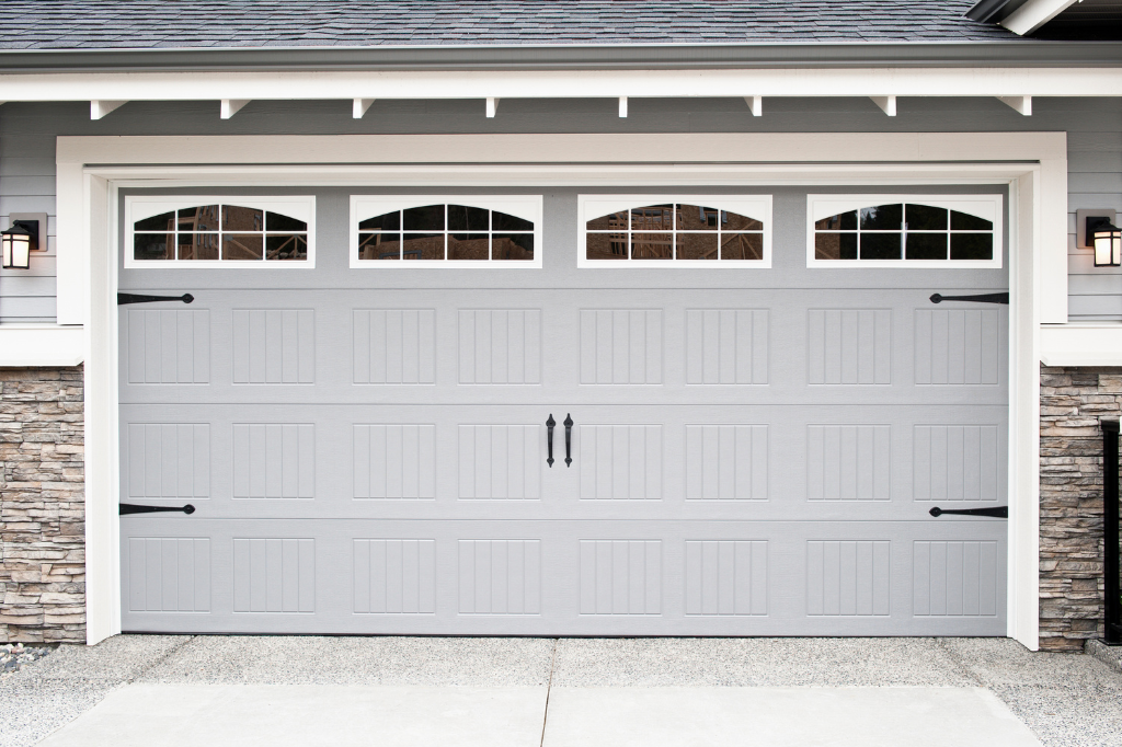 A large gray garage door with windows on the side of a house.
