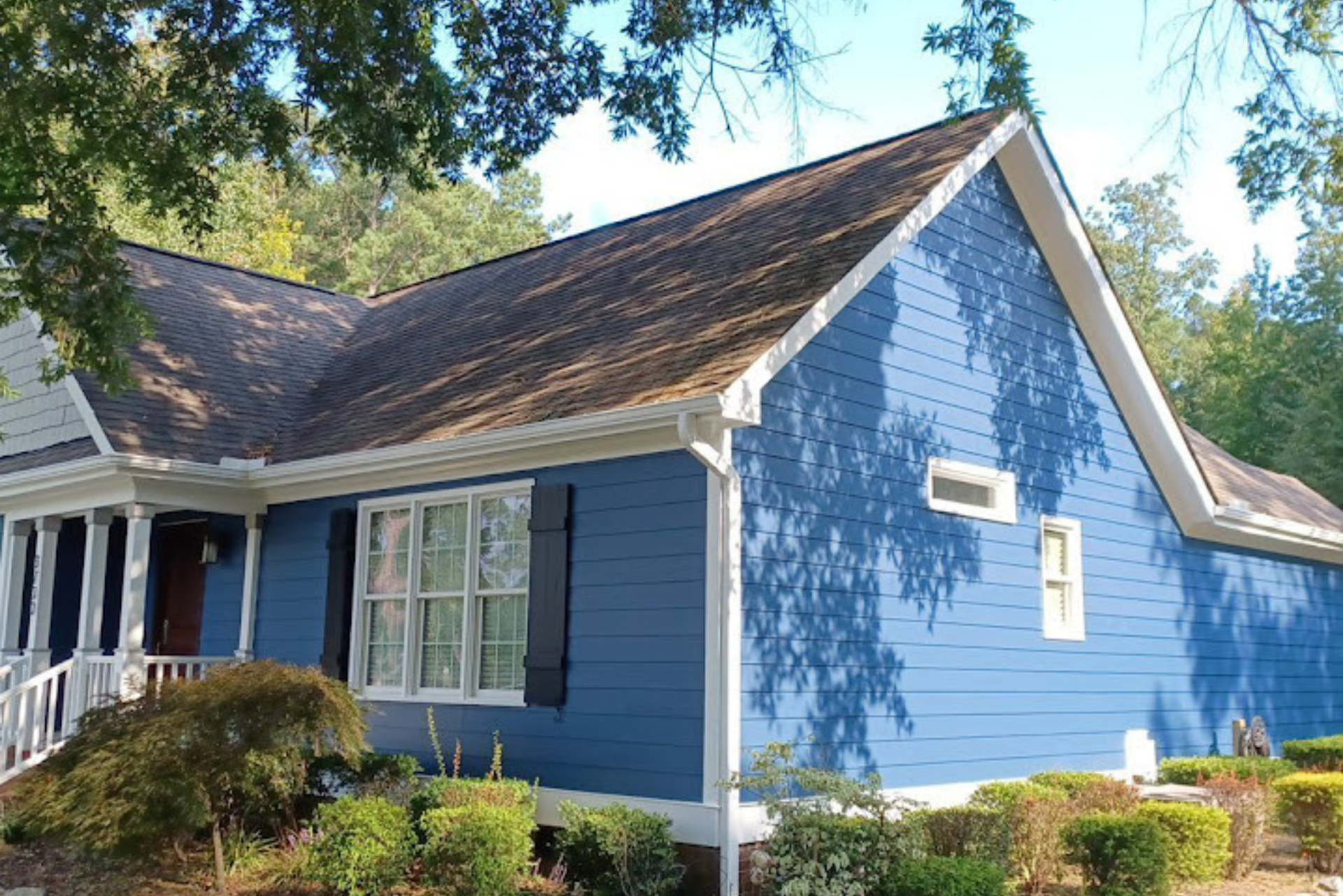 A blue house with a brown roof and black shutters