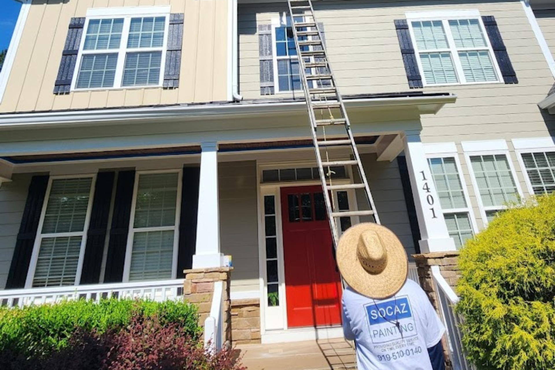 A man is standing on a ladder in front of a house.