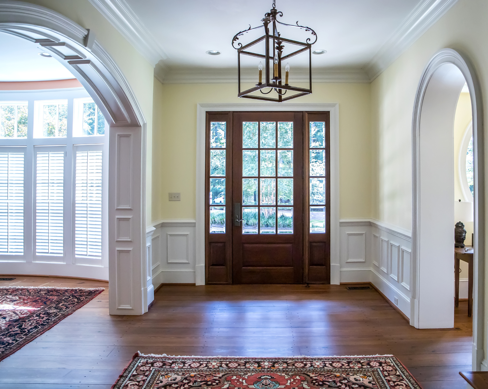 A hallway with a rug on the floor and a chandelier hanging from the ceiling