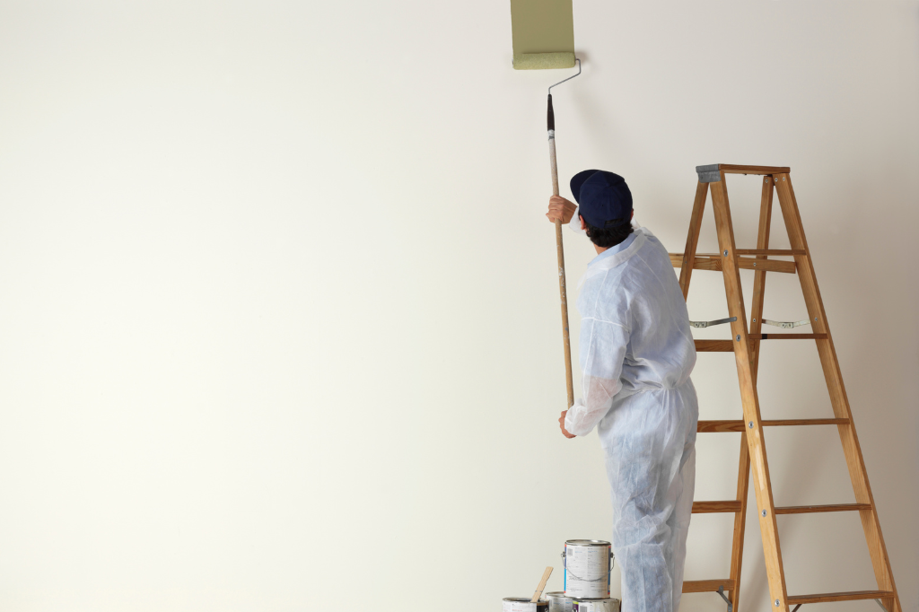 A man is painting a wall next to a ladder.