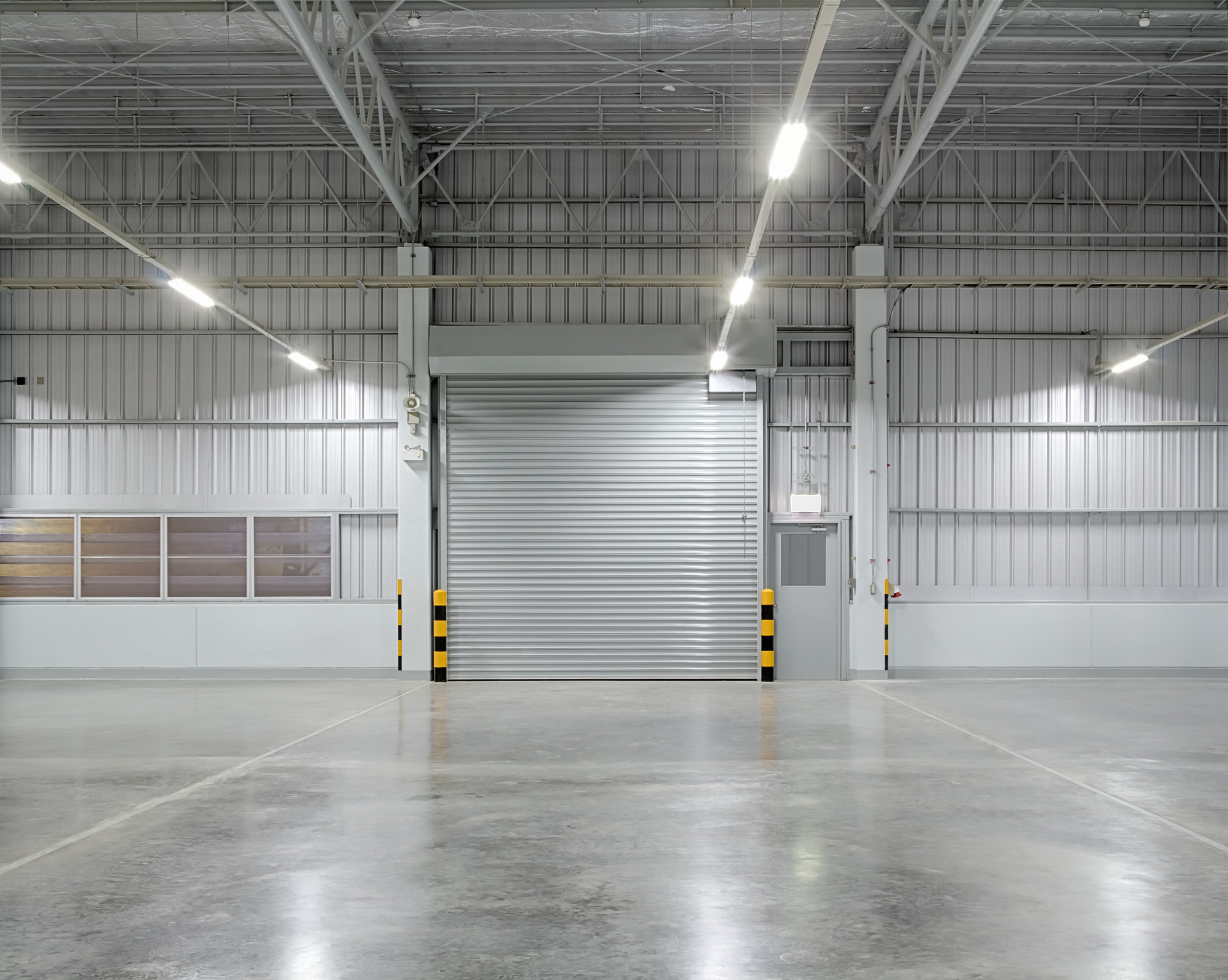 A large empty warehouse with a concrete floor and a sliding door.