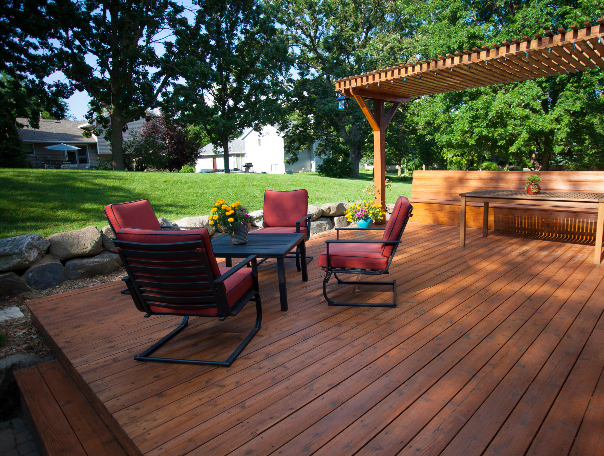 A wooden deck with a table and chairs under a pergola.