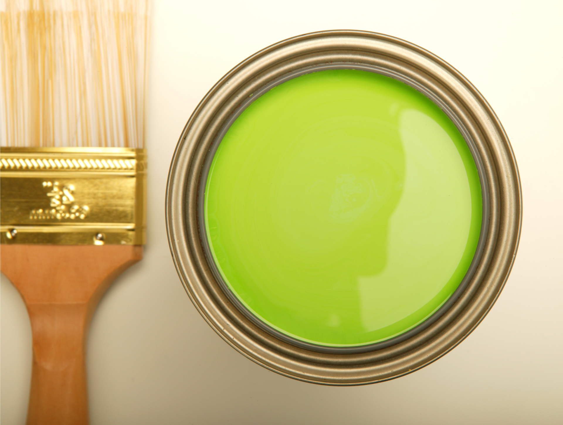 A can of green paint next to a brush