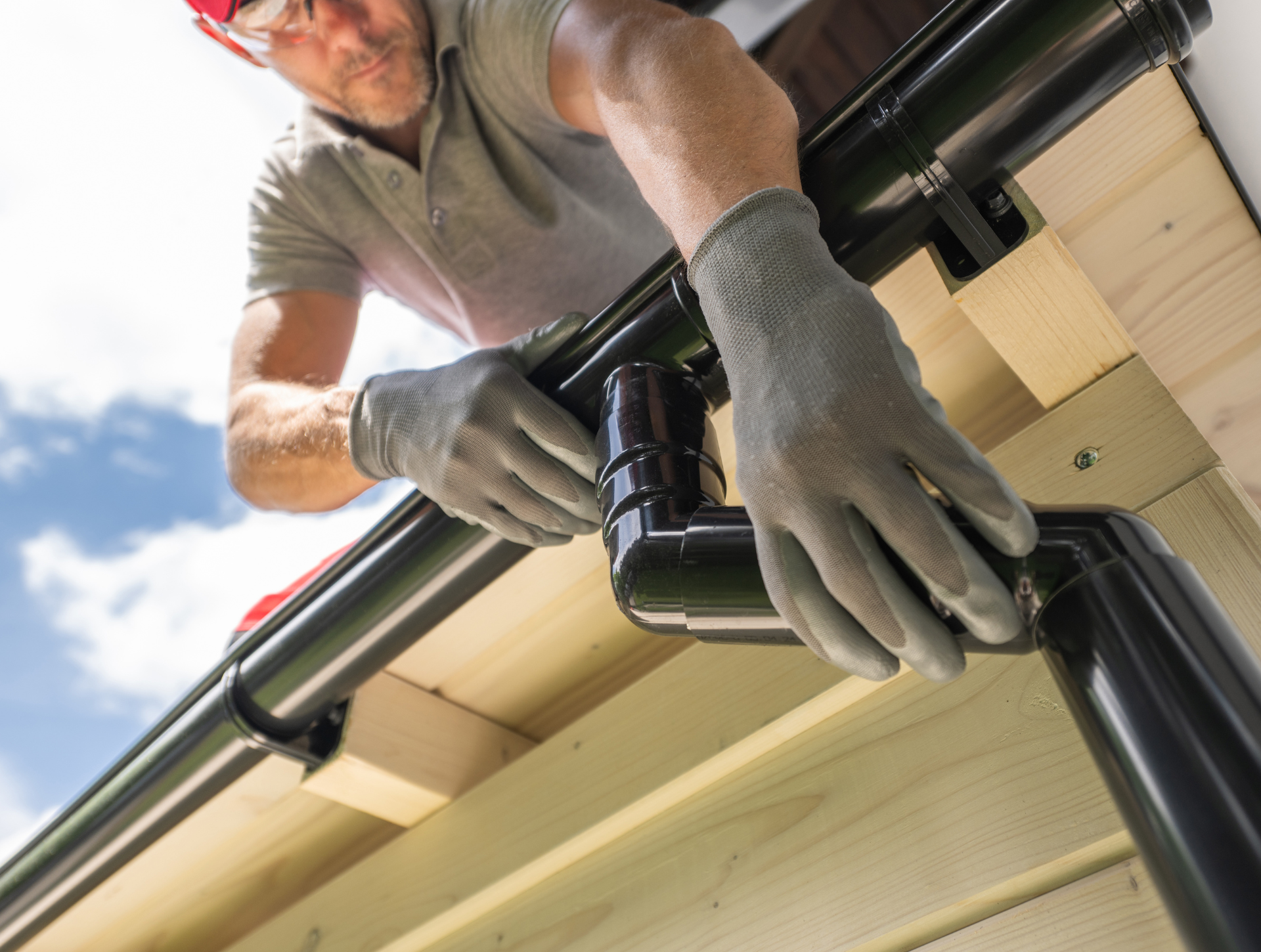 A man is installing a gutter on the roof of a house.