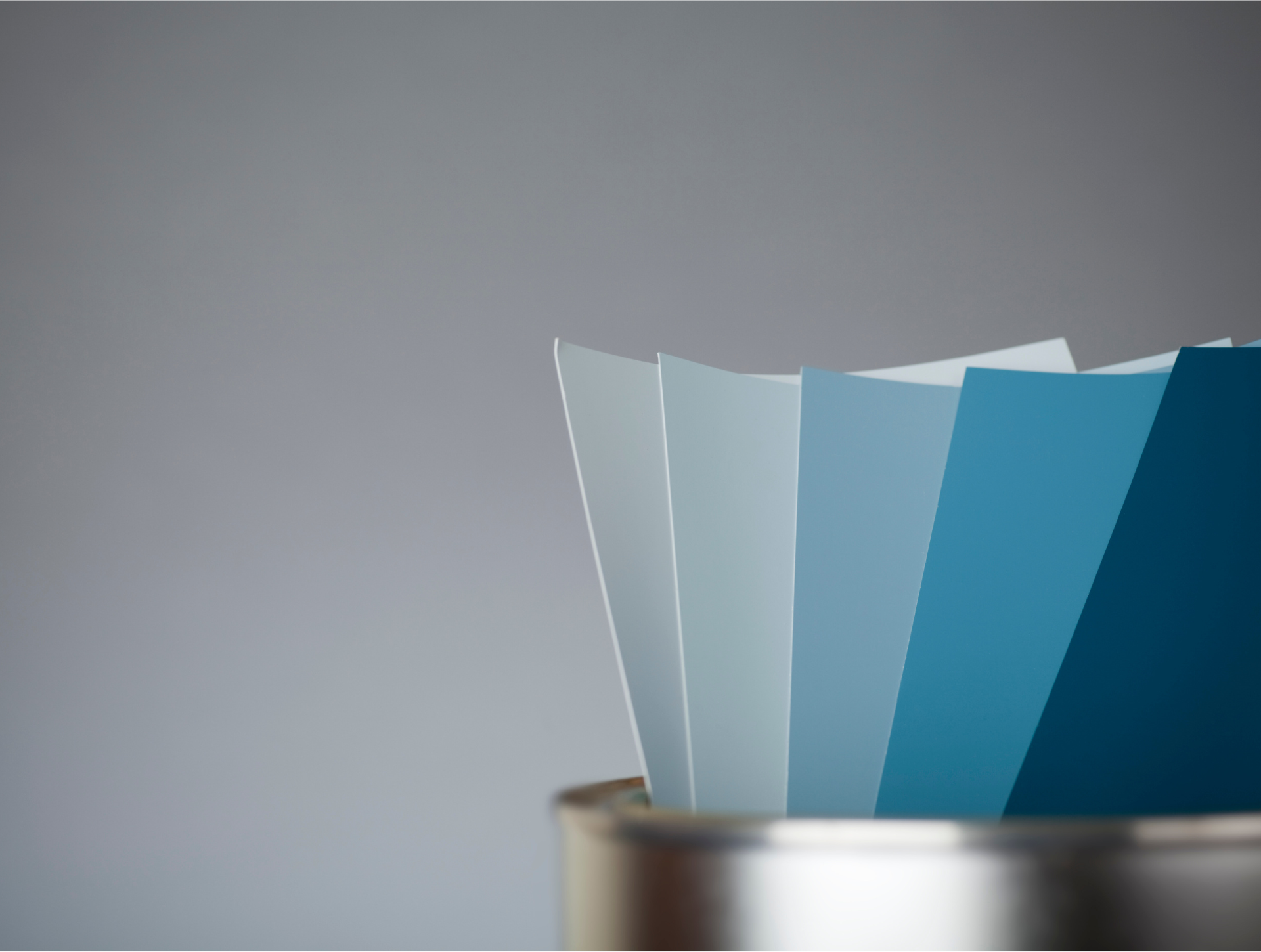 A metal bucket filled with different shades of blue paint.