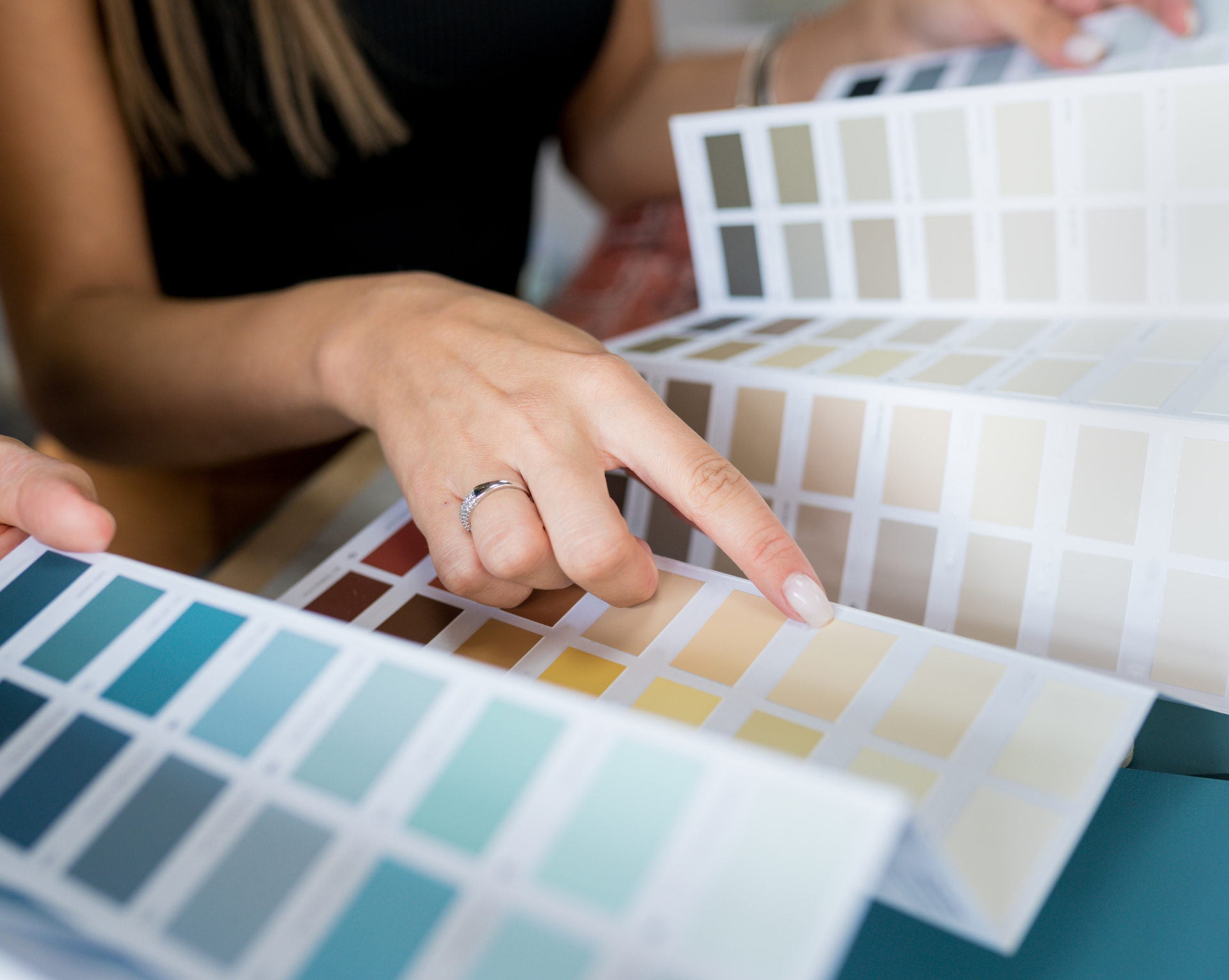 A woman with a ring on her finger is looking at a color palette.