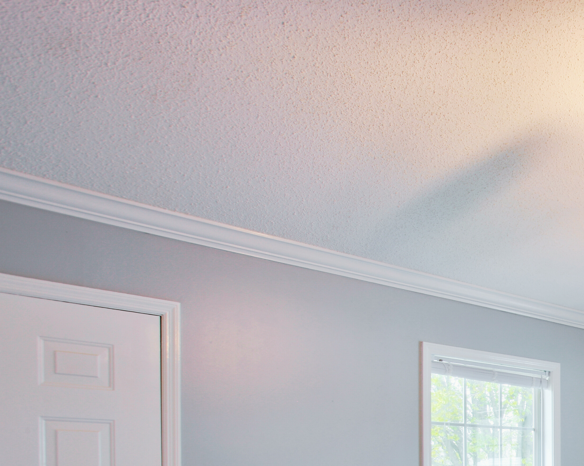 A bedroom with a ceiling fan and a window