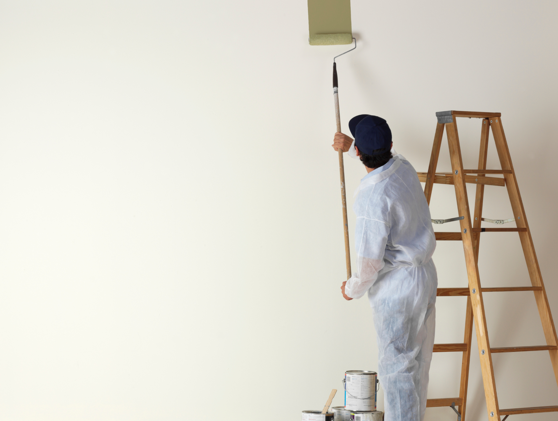 A man is standing on a ladder painting a wall.