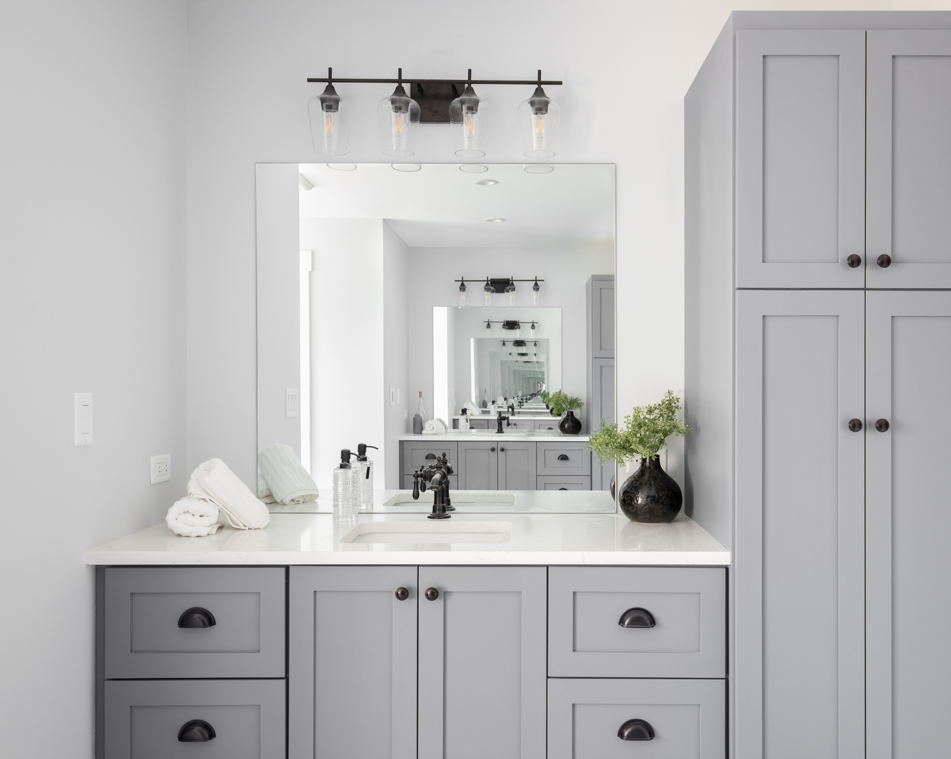 A bathroom with gray cabinets and a large mirror.