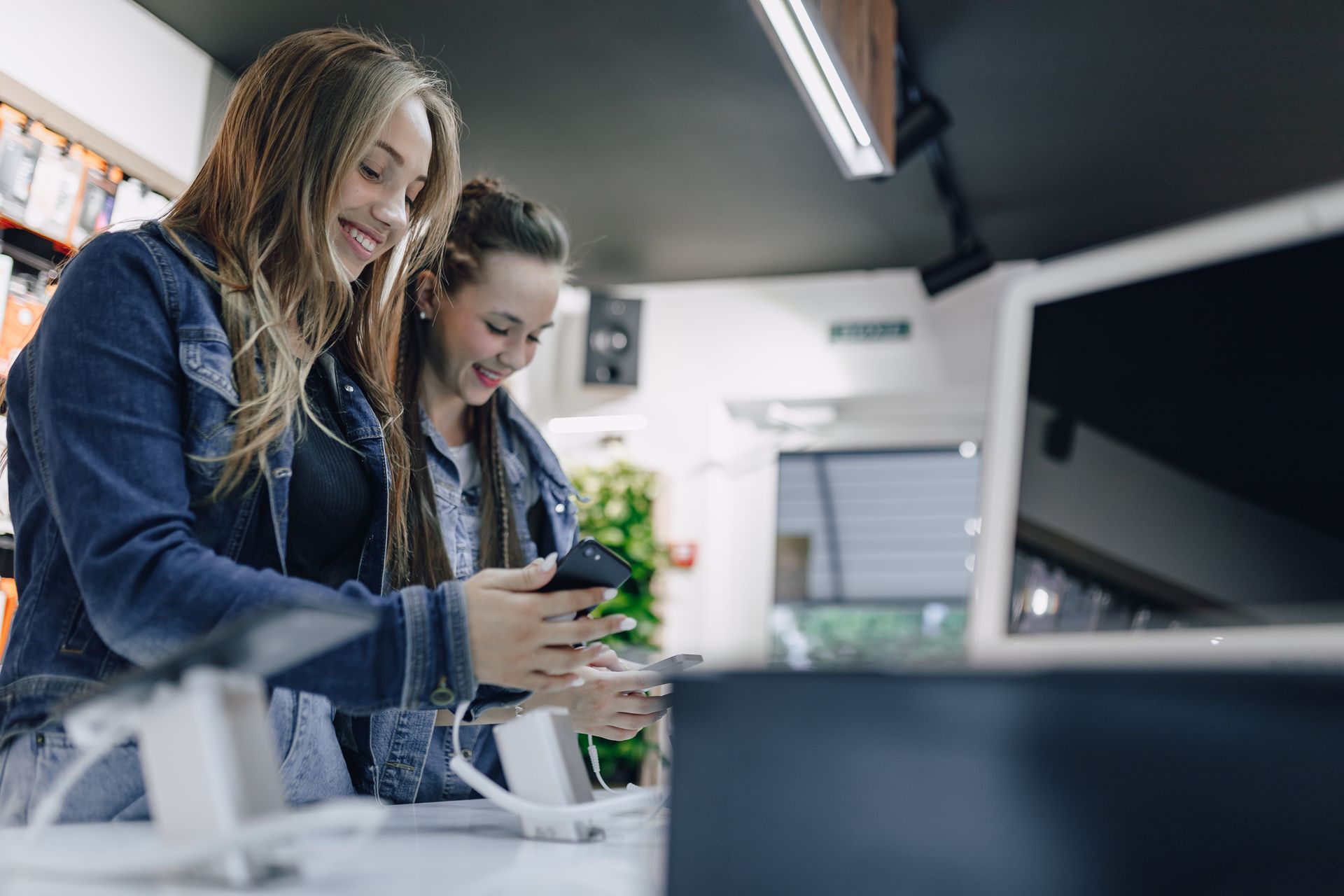 Two women are looking at a cell phone in a store.