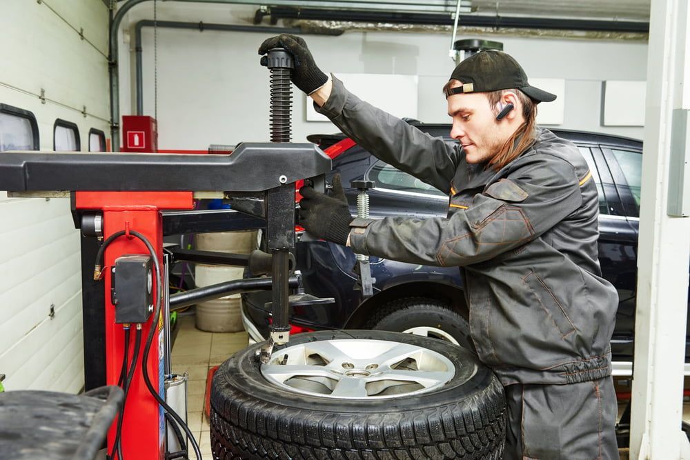 A Man Is Changing A Tire On A Machine In A Garage — Mullumbimby Automotive in Mullumbimby, NSW