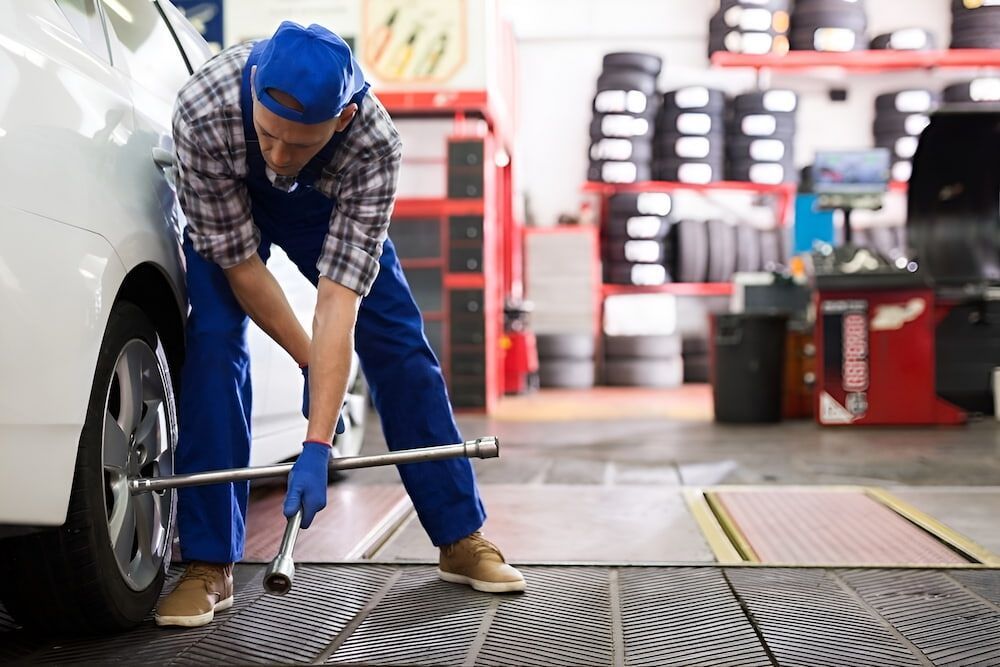 A Man Is Changing A Tire On A Car In A Garage — Mullumbimby Automotive in Mullumbimby, NSW