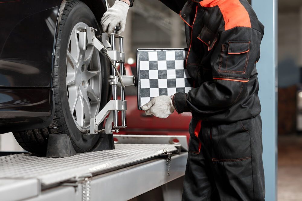 A Man Is Adjusting A Tire On A Car In A Garage — Mullumbimby Automotive in Mullumbimby, NSW