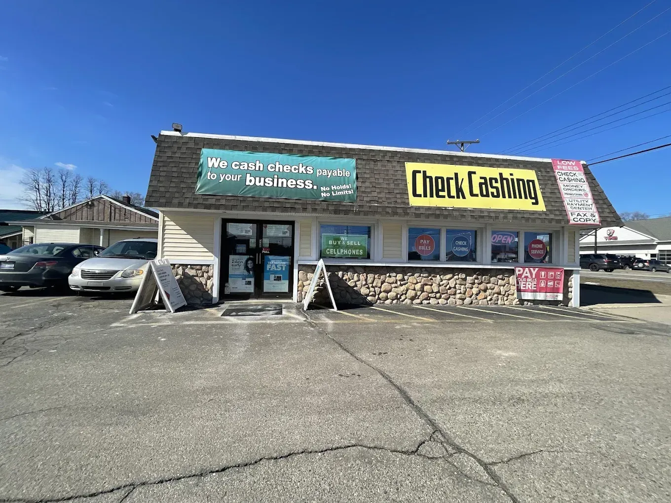 A check cashing store with cars parked in front of it.