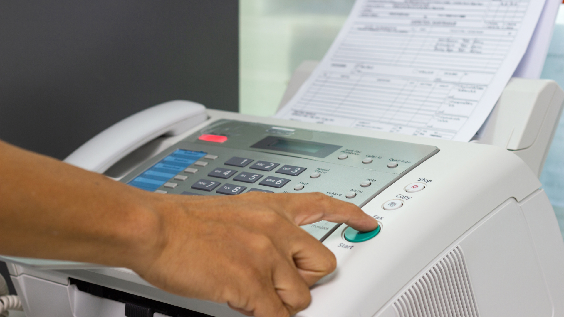 A person is pressing a button on a fax machine.