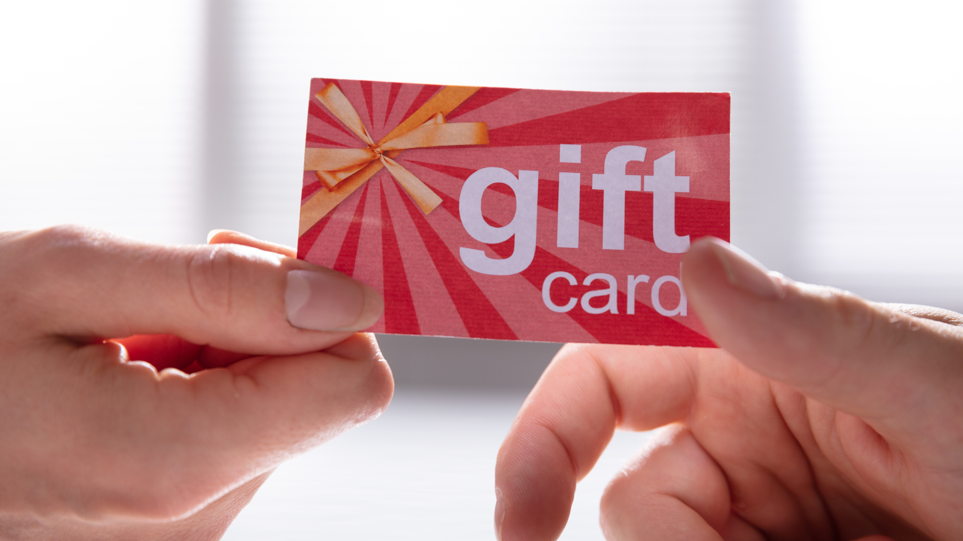 Two people are holding a red gift card that says gift card