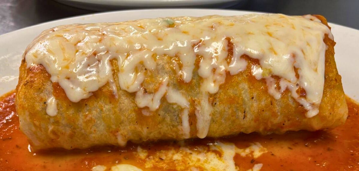 Burrito suiza topped with sauce and melted cheese