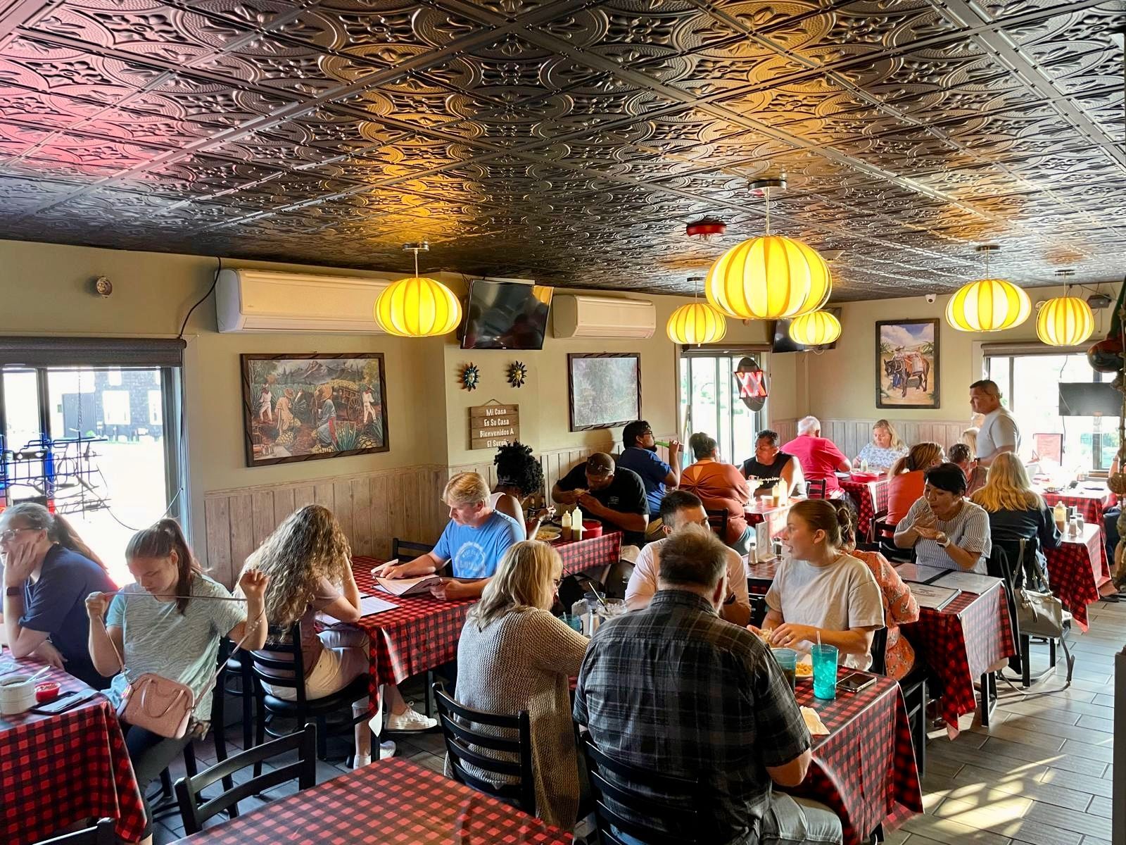 Guests eating and hanging out inside El Sureño near the bar
