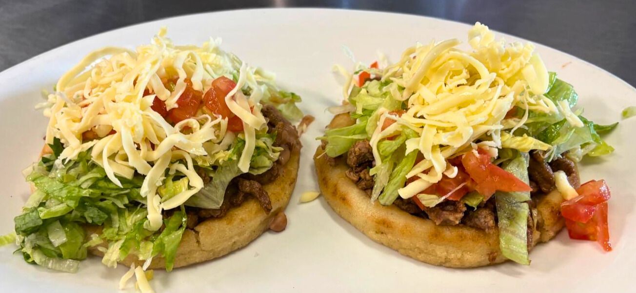 Steak sopes topped with lettuce, tomato, cheese, and crema