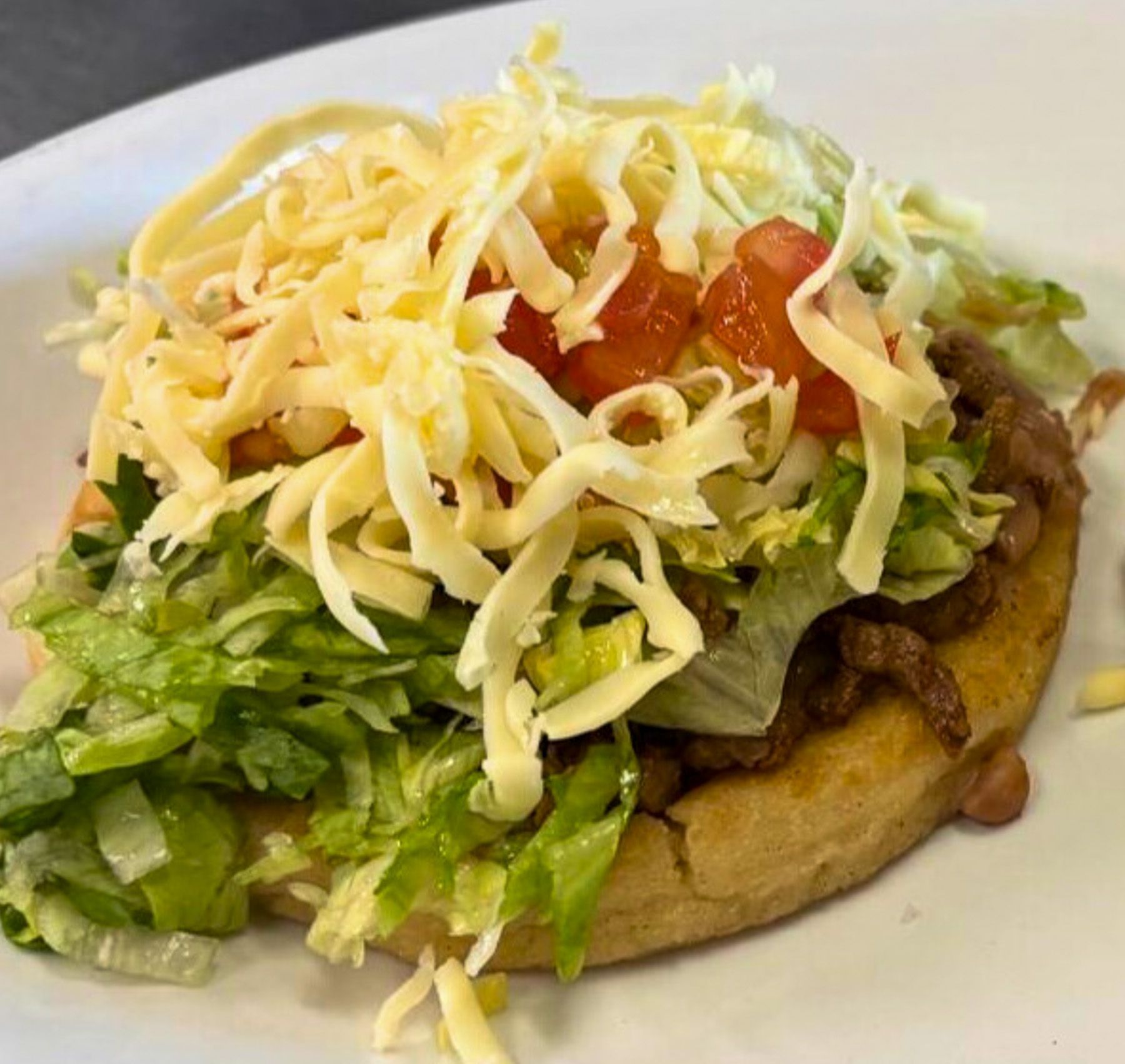 Steak sopes topped with lettuce, tomato, cheese, and crema