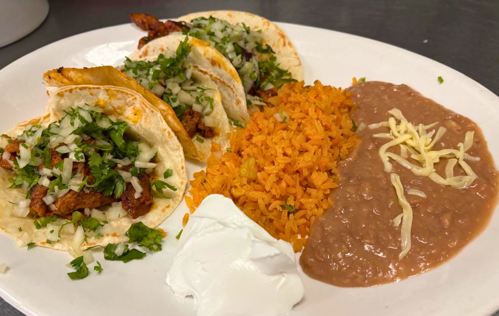 Al pastor tacos with rice, beans, cilantro, and onion