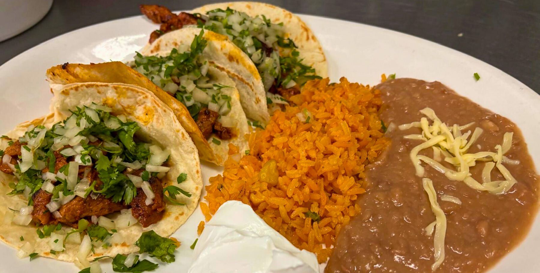 Al pastor tacos with rice, beans, cilantro, and onion